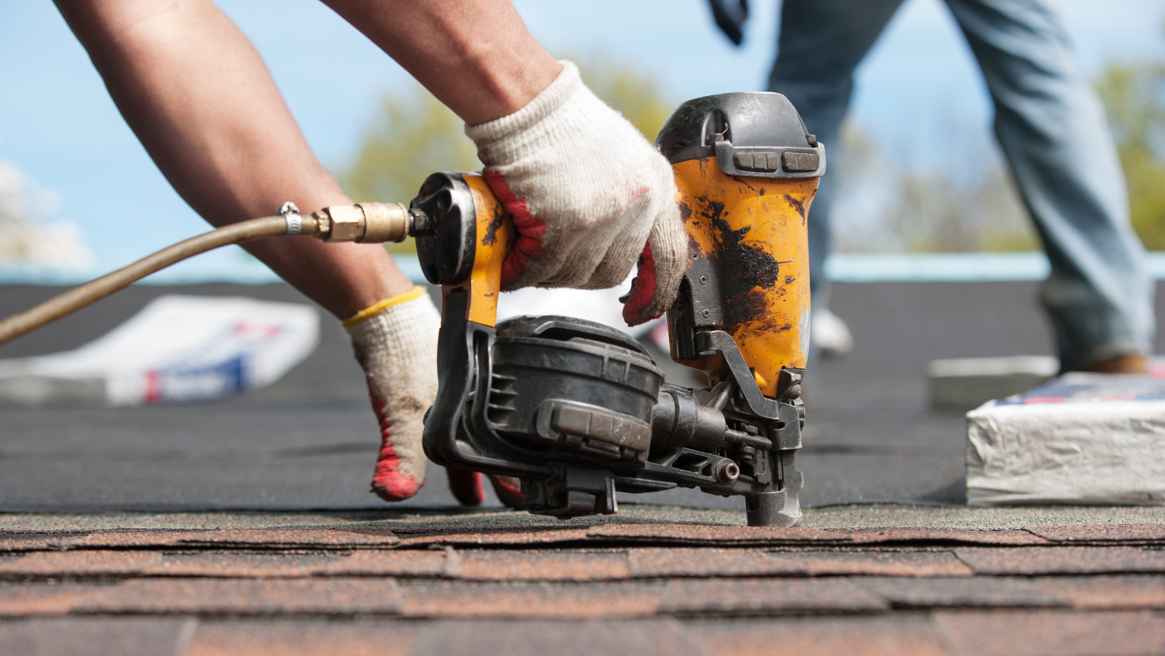 Roofing crew member using a nailgun during a professional roof repair
