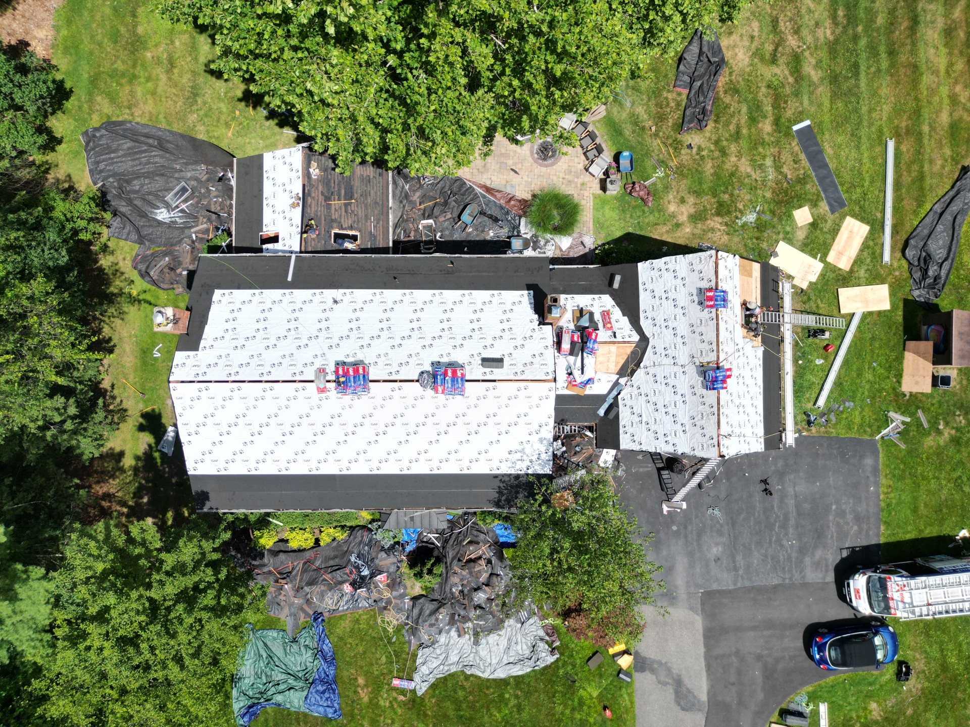 Overhead view of a Hudson Valley roof replacement showing white GAF underlayment, exposed decking, and shingle bundles mid-install