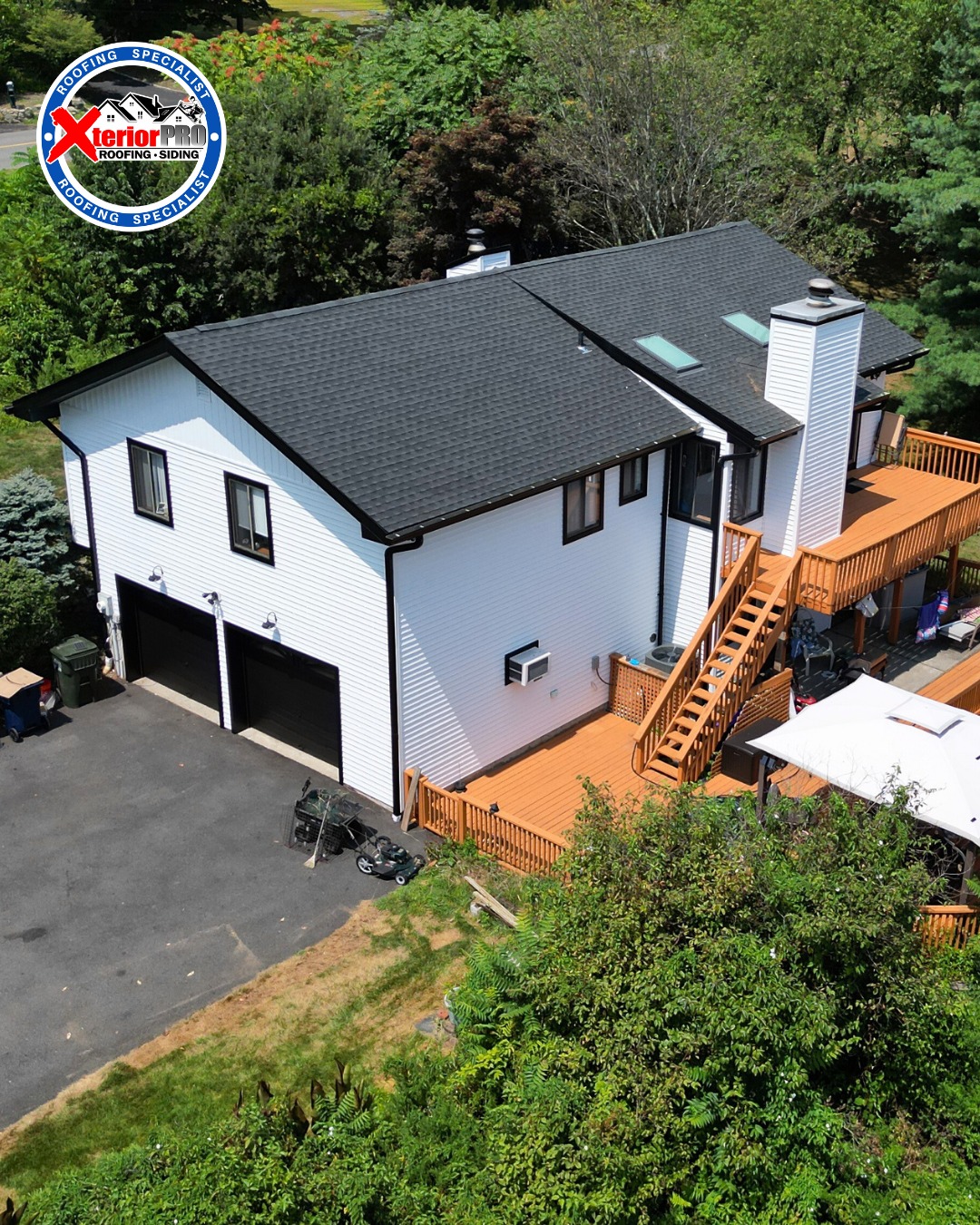 Rear aerial view of a home with a new GAF Timberline HDZ charcoal roof and white siding